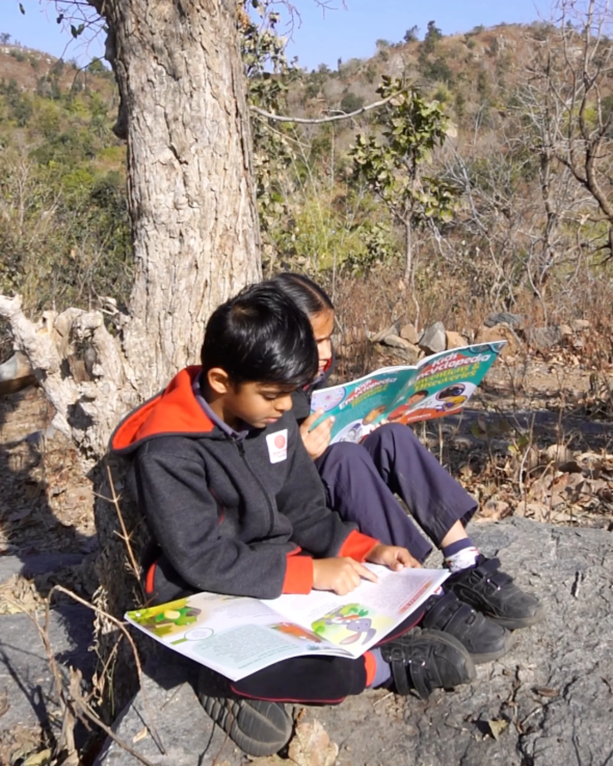Children Reading Books Outdoors In Nature