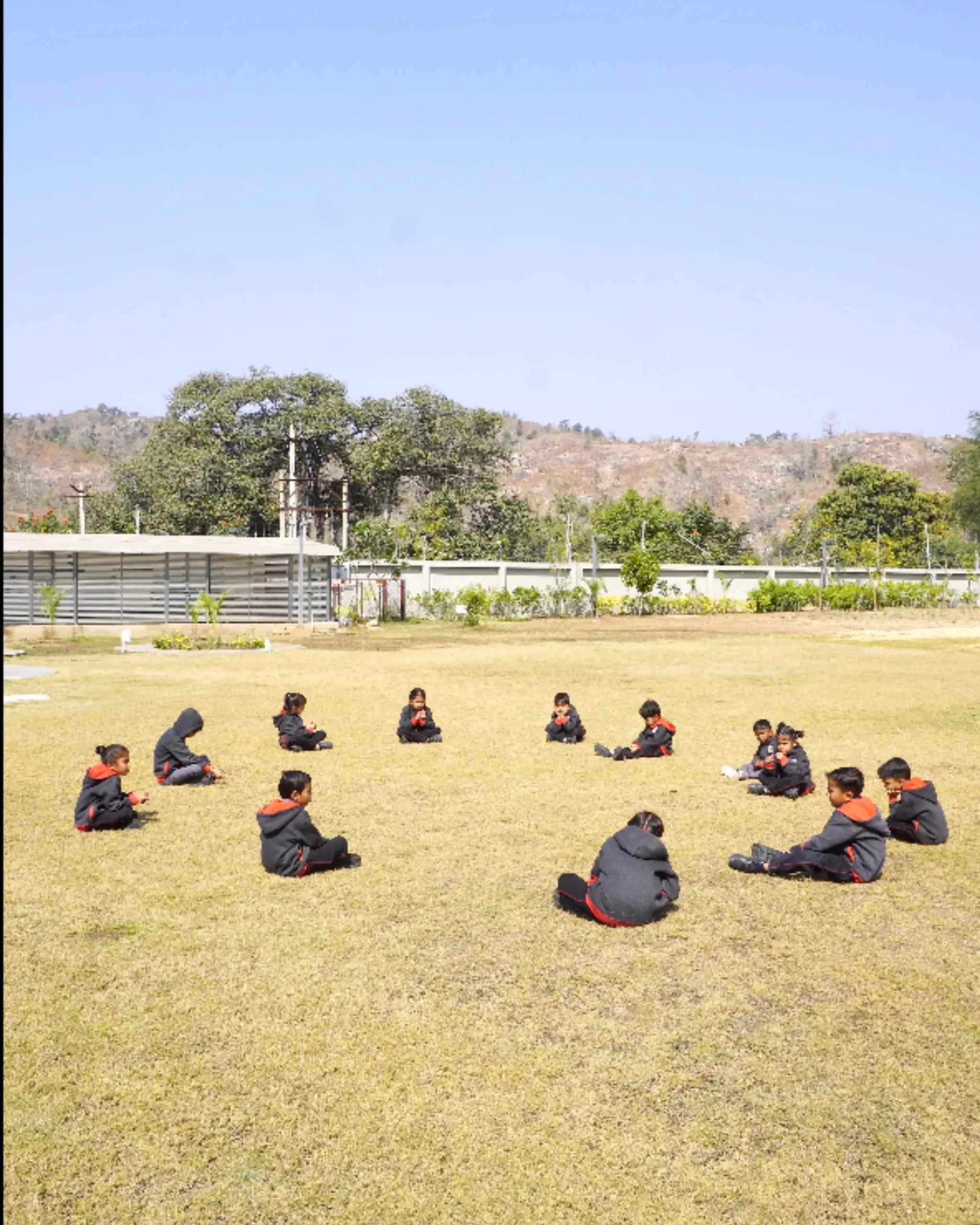 Children Sitting In A Circle On Grassy Field