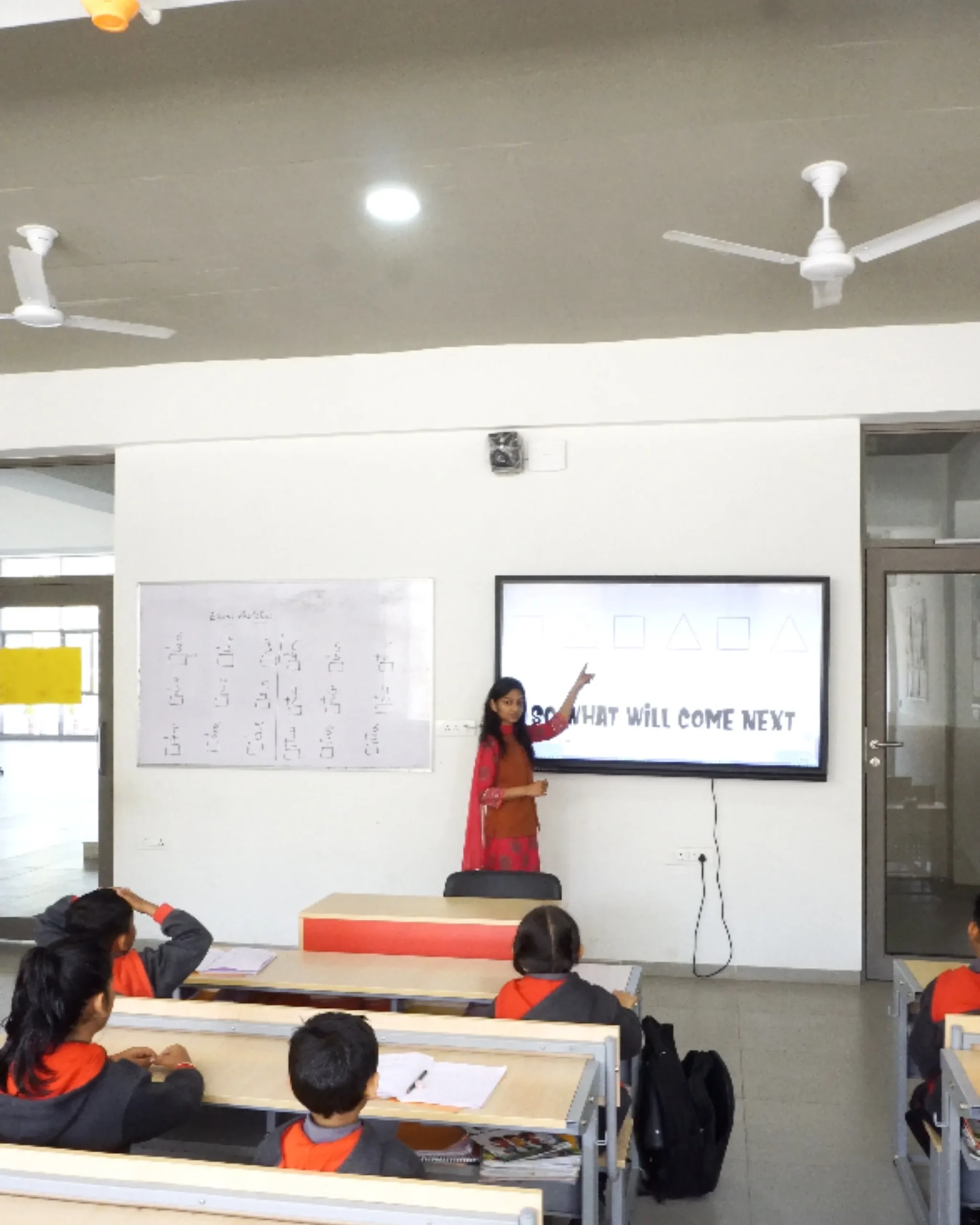 Teacher Pointing At Digital Screen In Classroom